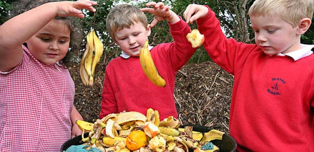 Kids simultaneously dropping food items into compost