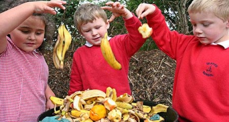 Kids simultaneously dropping food items into compost