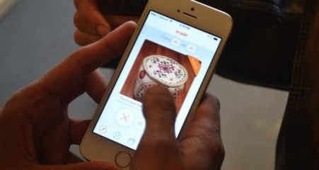 A hand swiping the Tradr app on iPhone